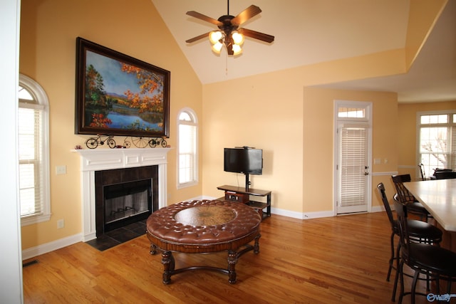 living room featuring a fireplace, wood-type flooring, ceiling fan, and vaulted ceiling