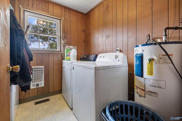 laundry room with washing machine and clothes dryer, heating unit, wood walls, crown molding, and electric water heater