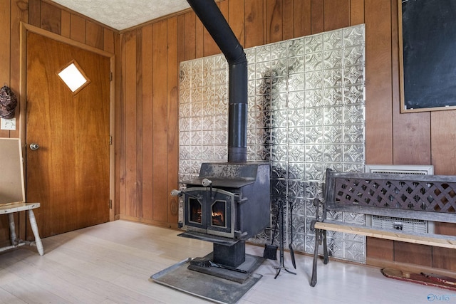 living room featuring light hardwood / wood-style floors, wood walls, and a wood stove