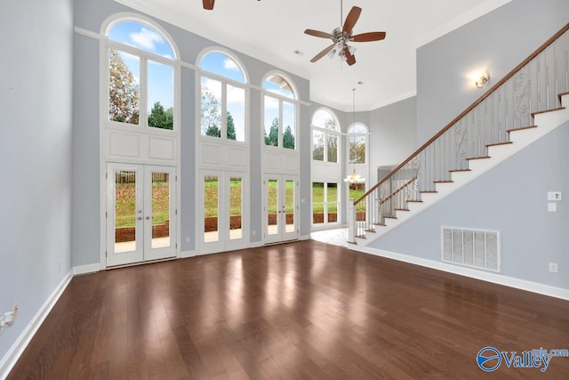 unfurnished living room with dark hardwood / wood-style flooring, plenty of natural light, ceiling fan with notable chandelier, and french doors