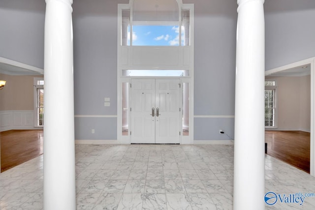 foyer featuring decorative columns, a wealth of natural light, and light hardwood / wood-style floors