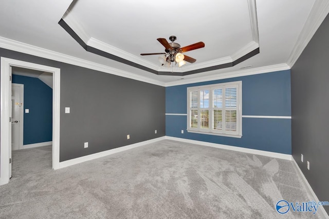 empty room with a raised ceiling, crown molding, ceiling fan, and light carpet