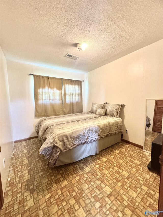 32 Kirby Rd, Hillsboro, AL 35643 - bedroom featuring baseboards, a textured ceiling, and brick patterned floors