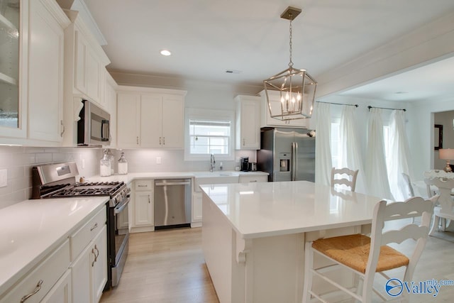 kitchen with a breakfast bar area, appliances with stainless steel finishes, white cabinets, and backsplash