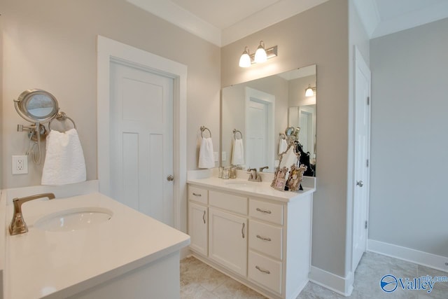 bathroom with crown molding, baseboards, two vanities, and a sink