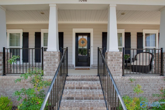 doorway to property featuring covered porch and brick siding