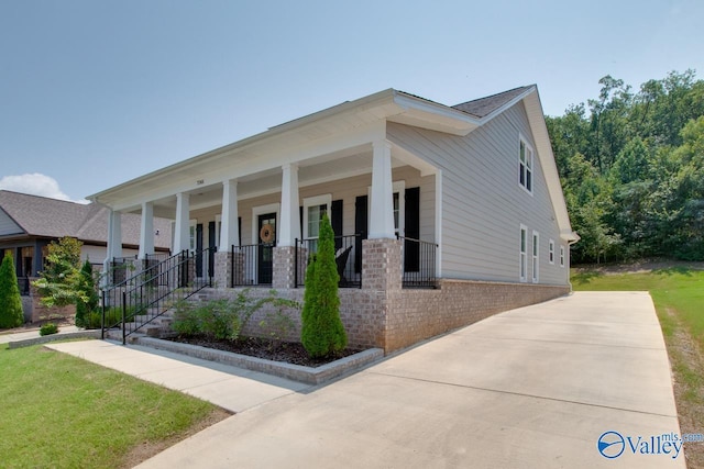 view of front of house featuring a porch, a front yard, and brick siding