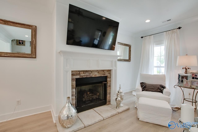 living area with recessed lighting, a stone fireplace, light wood-style flooring, and baseboards