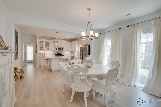 dining room with crown molding, light wood-type flooring, visible vents, and a healthy amount of sunlight