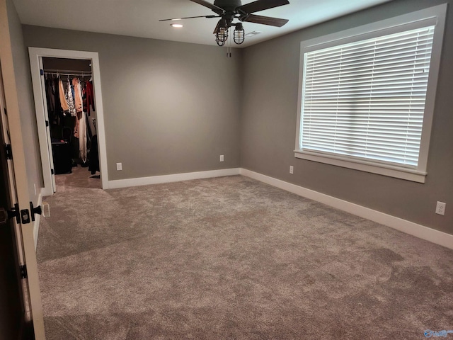 unfurnished bedroom with a closet, a spacious closet, carpet, and baseboards