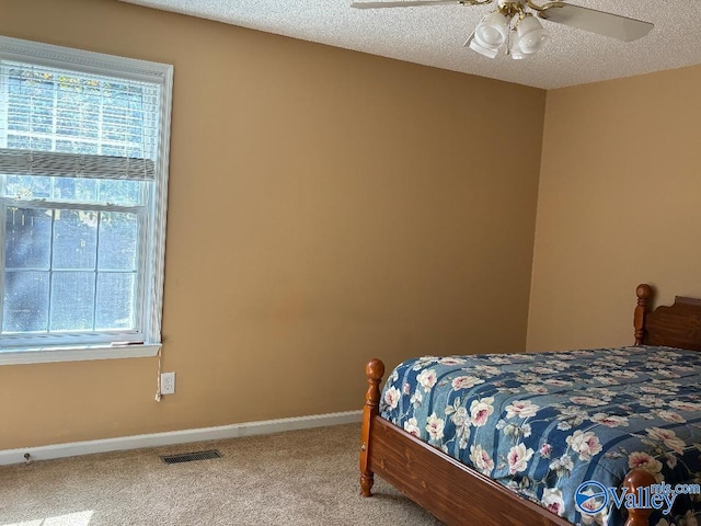 carpeted bedroom featuring ceiling fan, a textured ceiling, and multiple windows