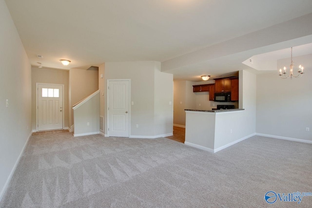 unfurnished living room with an inviting chandelier and light colored carpet