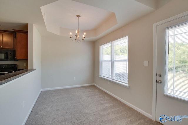 unfurnished dining area featuring a chandelier, light carpet, and a raised ceiling