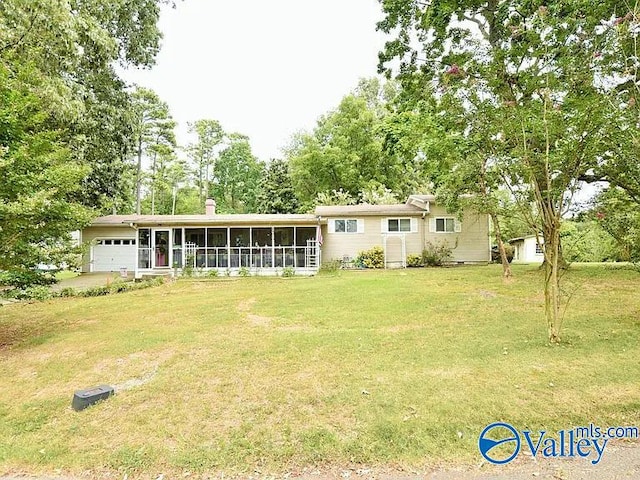 back of house with a garage, a lawn, and a sunroom