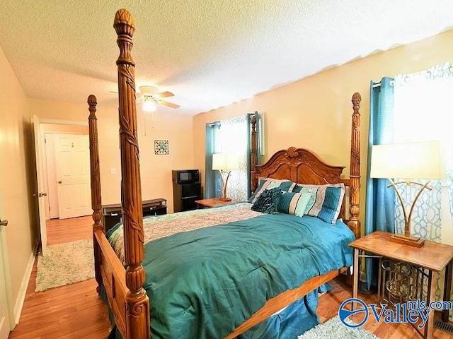 bedroom featuring ceiling fan, wood-type flooring, and a textured ceiling