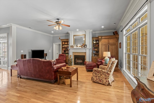 living room with light wood finished floors, a fireplace, ornamental molding, recessed lighting, and a ceiling fan