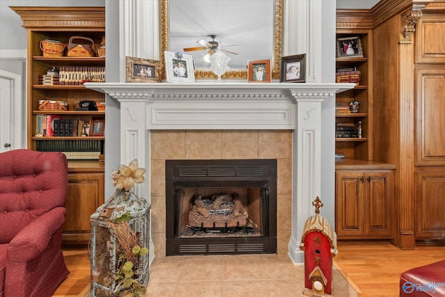 interior space with ceiling fan, wood finished floors, a tiled fireplace, and a baseboard radiator