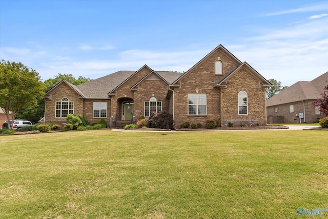 traditional-style house with a front lawn, brick siding, and roof with shingles