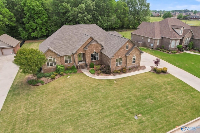 view of front of house with driveway, brick siding, a shingled roof, and a front lawn