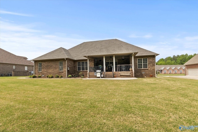 view of front of property with a front lawn, brick siding, and roof with shingles