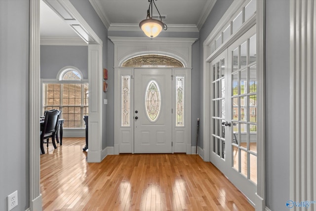 foyer with baseboards, ornamental molding, french doors, and light wood finished floors