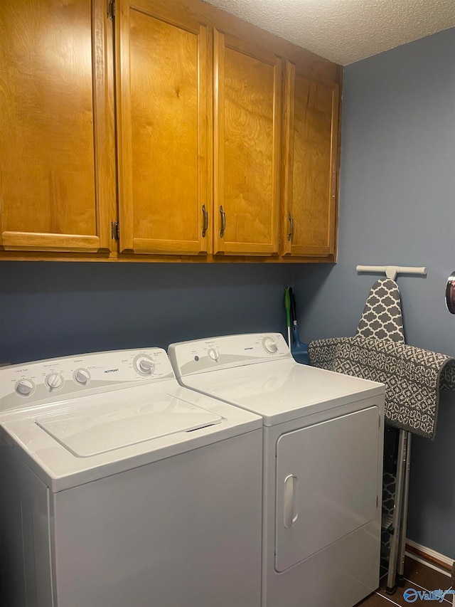 laundry room with a textured ceiling, washing machine and clothes dryer, and cabinet space