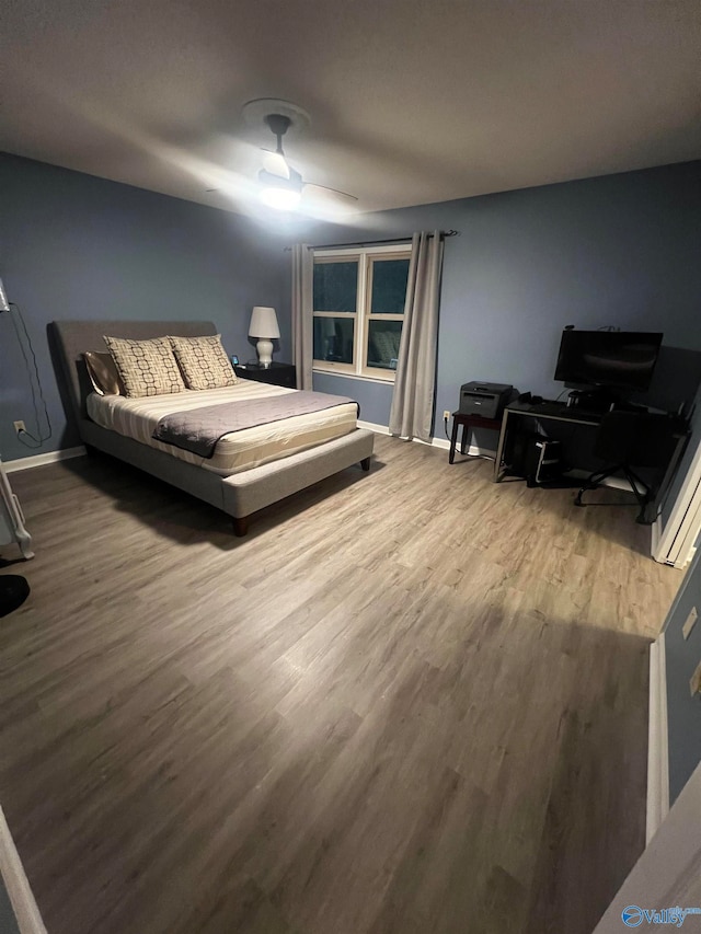 bedroom with ceiling fan, wood finished floors, and baseboards