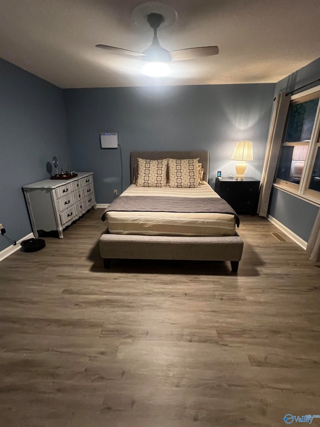 bedroom featuring ceiling fan, baseboards, and wood finished floors