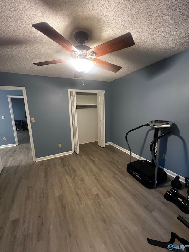 workout room featuring a textured ceiling, dark wood finished floors, and baseboards