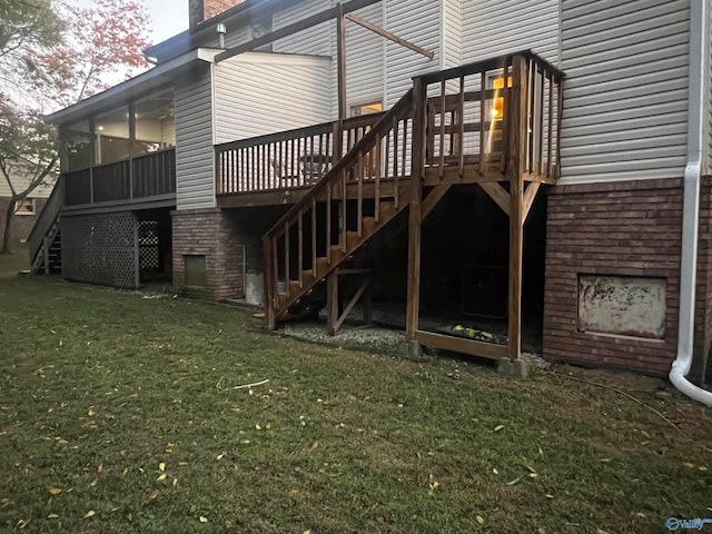 rear view of house with a deck, a sunroom, stairway, and a lawn