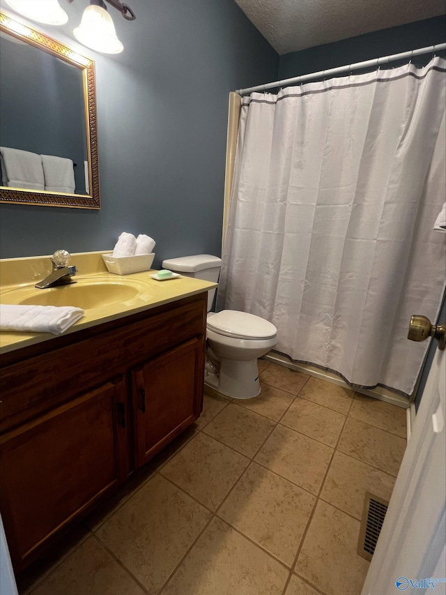 bathroom featuring a textured ceiling, toilet, vanity, visible vents, and tile patterned floors