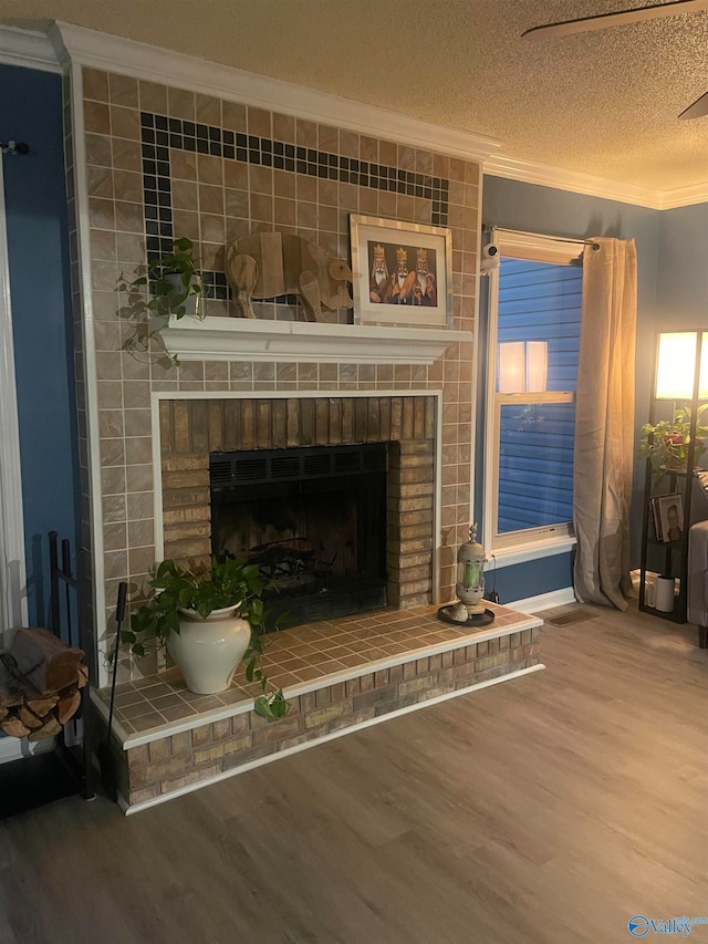 details featuring ornamental molding, a brick fireplace, a textured ceiling, and wood finished floors