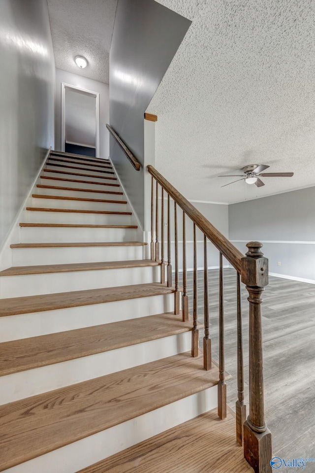 stairs featuring a textured ceiling, ceiling fan, and hardwood / wood-style floors