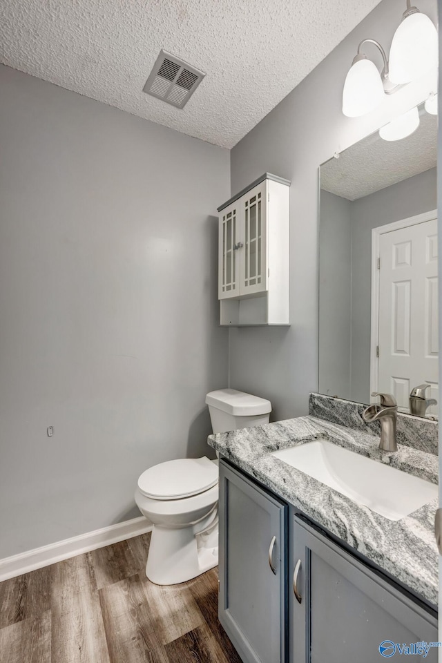 bathroom featuring vanity, a textured ceiling, hardwood / wood-style flooring, and toilet