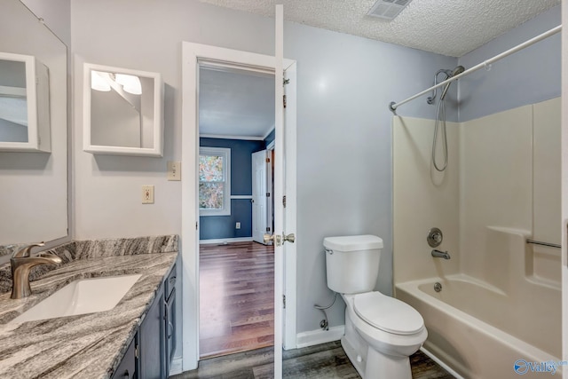 full bathroom with vanity, hardwood / wood-style flooring, shower / tub combination, toilet, and a textured ceiling