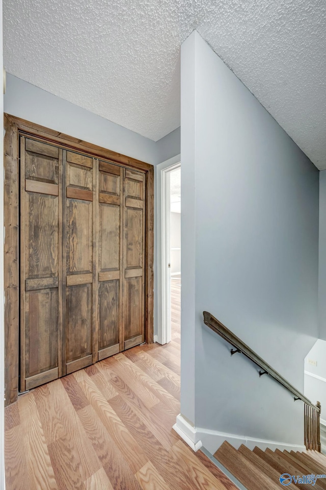 hall with light hardwood / wood-style flooring and a textured ceiling