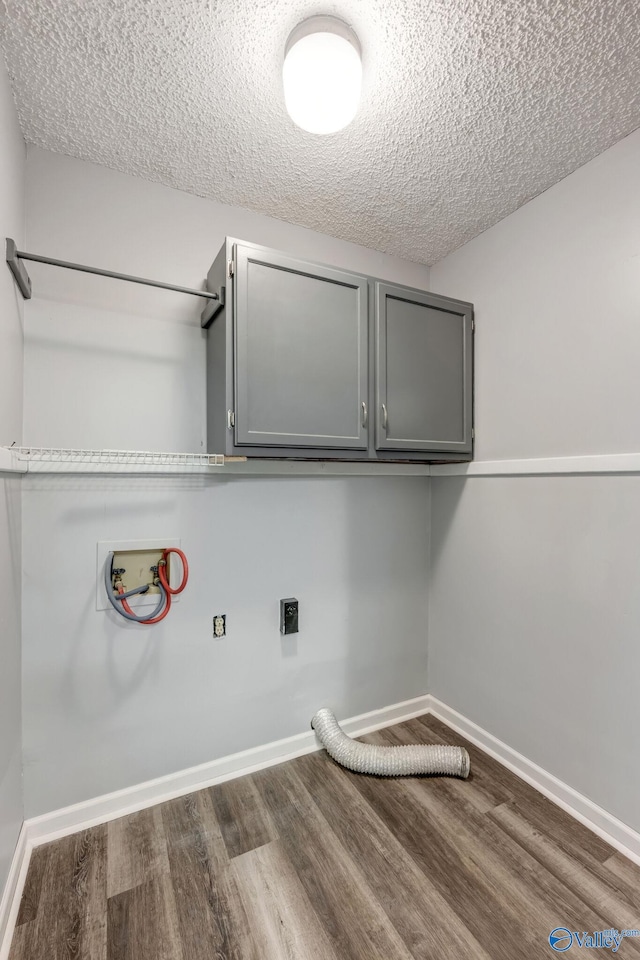 washroom featuring hookup for an electric dryer, dark hardwood / wood-style floors, cabinets, and a textured ceiling