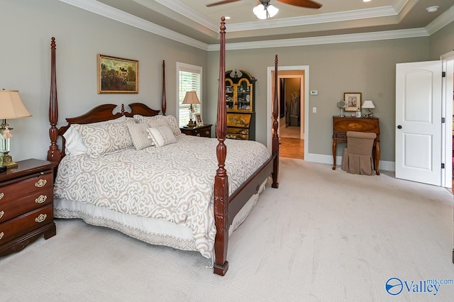 carpeted bedroom with ceiling fan, crown molding, and a tray ceiling