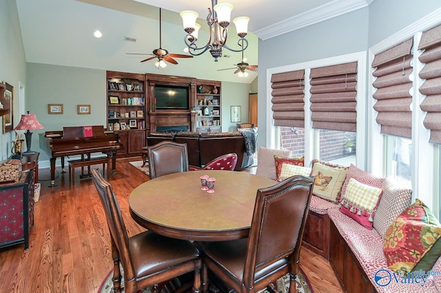 dining area with built in features, ceiling fan with notable chandelier, crown molding, and hardwood / wood-style floors