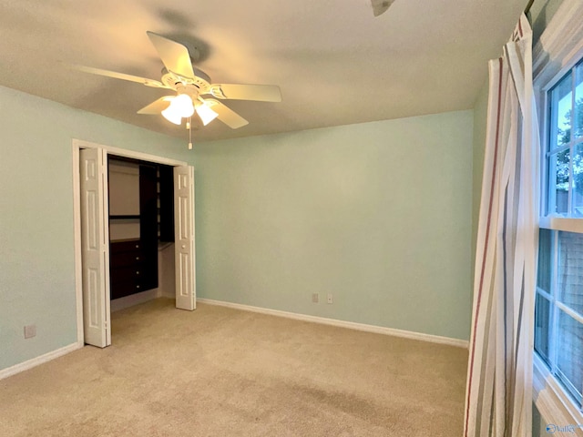 unfurnished bedroom featuring a closet, light colored carpet, and ceiling fan