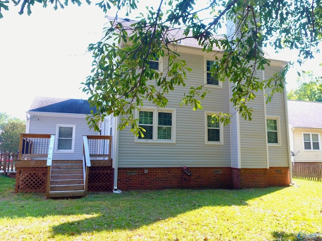 rear view of property featuring a wooden deck and a lawn