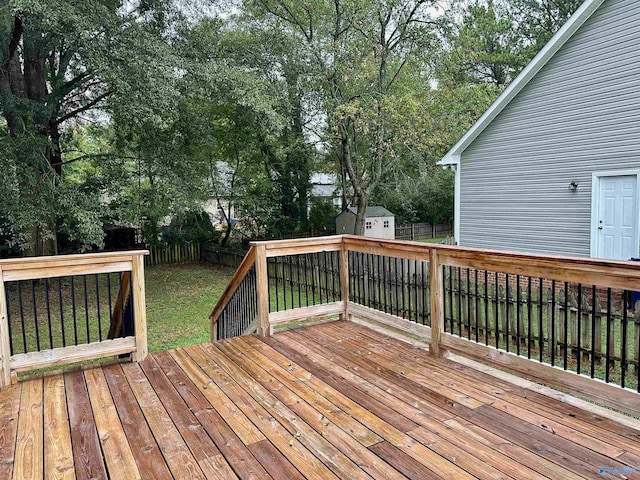 wooden deck featuring a storage unit and a lawn