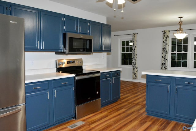 kitchen with appliances with stainless steel finishes, blue cabinetry, ceiling fan, and dark hardwood / wood-style floors