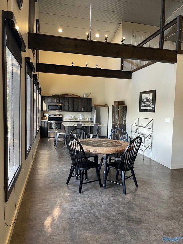 dining space with beam ceiling and a towering ceiling