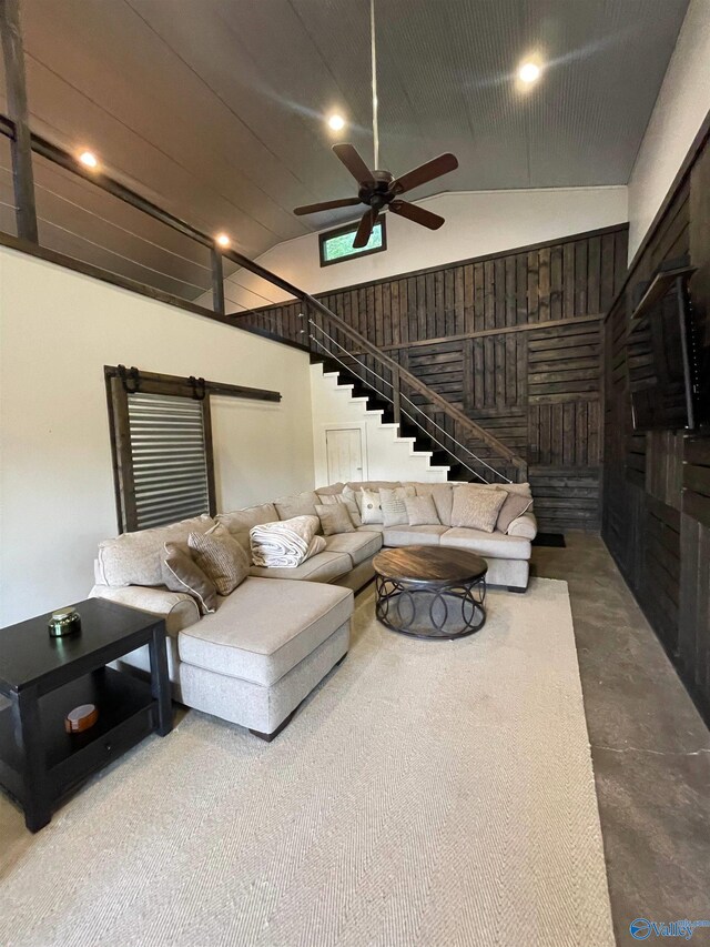 living room featuring a barn door, ceiling fan, and high vaulted ceiling