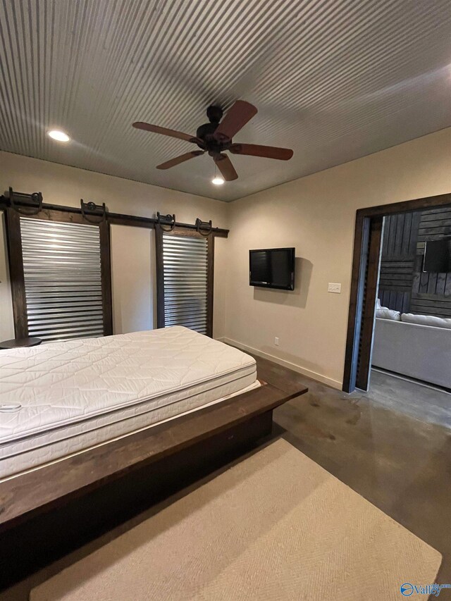 unfurnished bedroom featuring a barn door, ceiling fan, and carpet floors