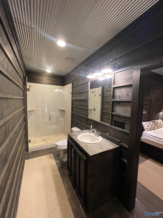 bathroom featuring wooden walls, a shower with door, toilet, and vanity