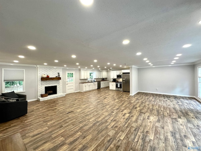 unfurnished living room featuring a wealth of natural light, crown molding, a fireplace, and dark hardwood / wood-style flooring