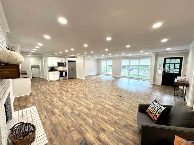 living room with light hardwood / wood-style floors, a healthy amount of sunlight, a fireplace, and ornamental molding