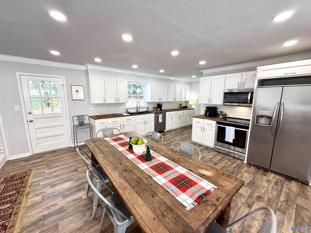 kitchen with wood-type flooring, pendant lighting, butcher block counters, and white cabinetry